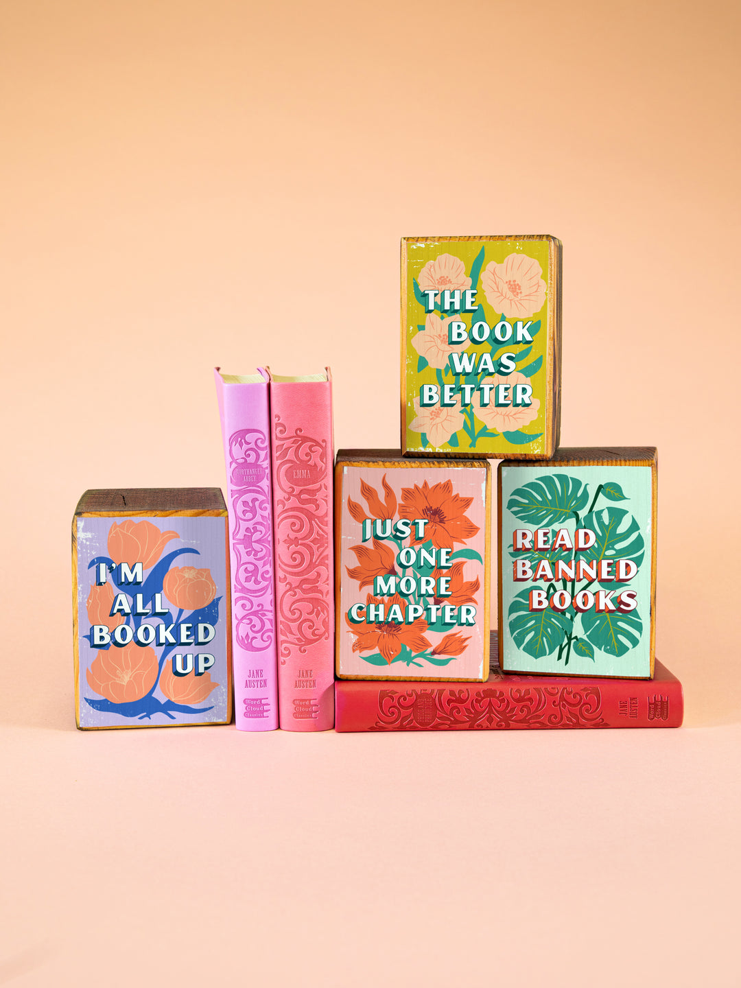 stack of four wood bookends featuring colorful flower illustrations with bookish sayings, "I&