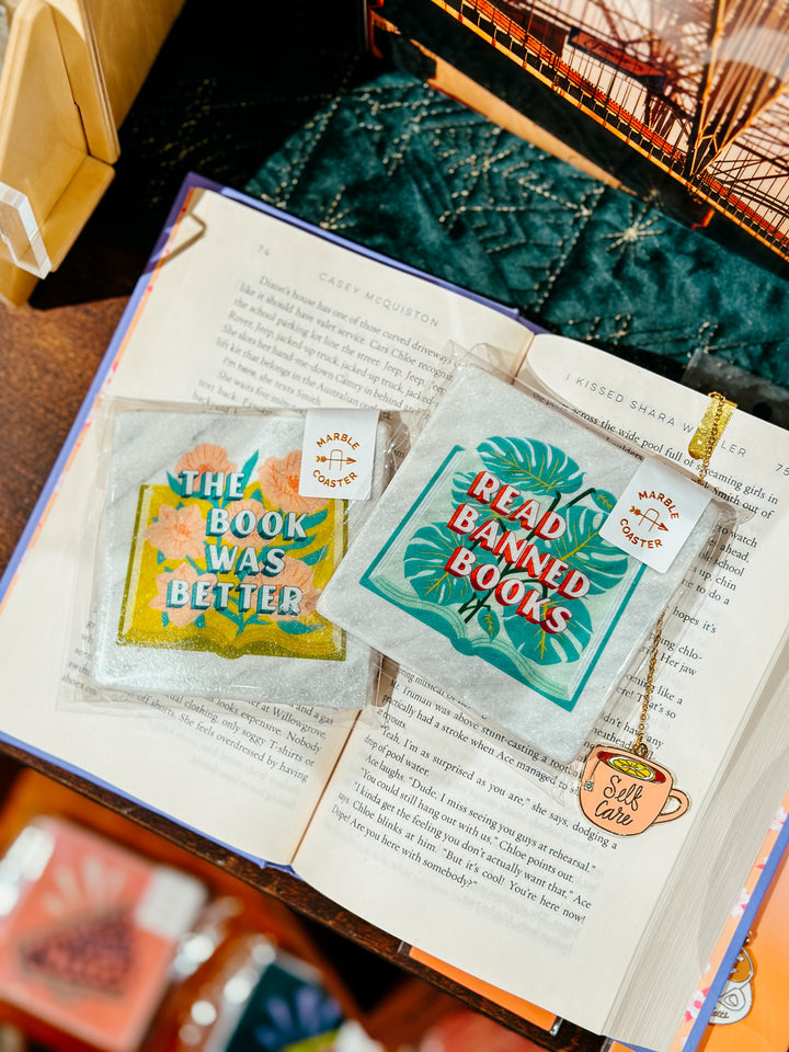 Read banned books coaster on book with self care bookmark and beside the book was better coaster