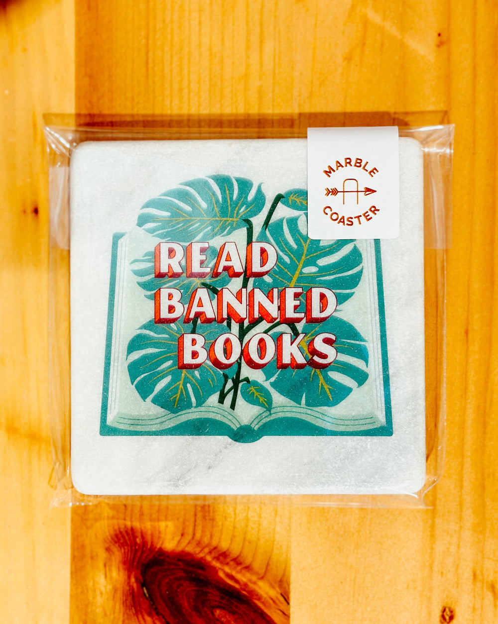Read Banned Books marble coaster on a wood table
