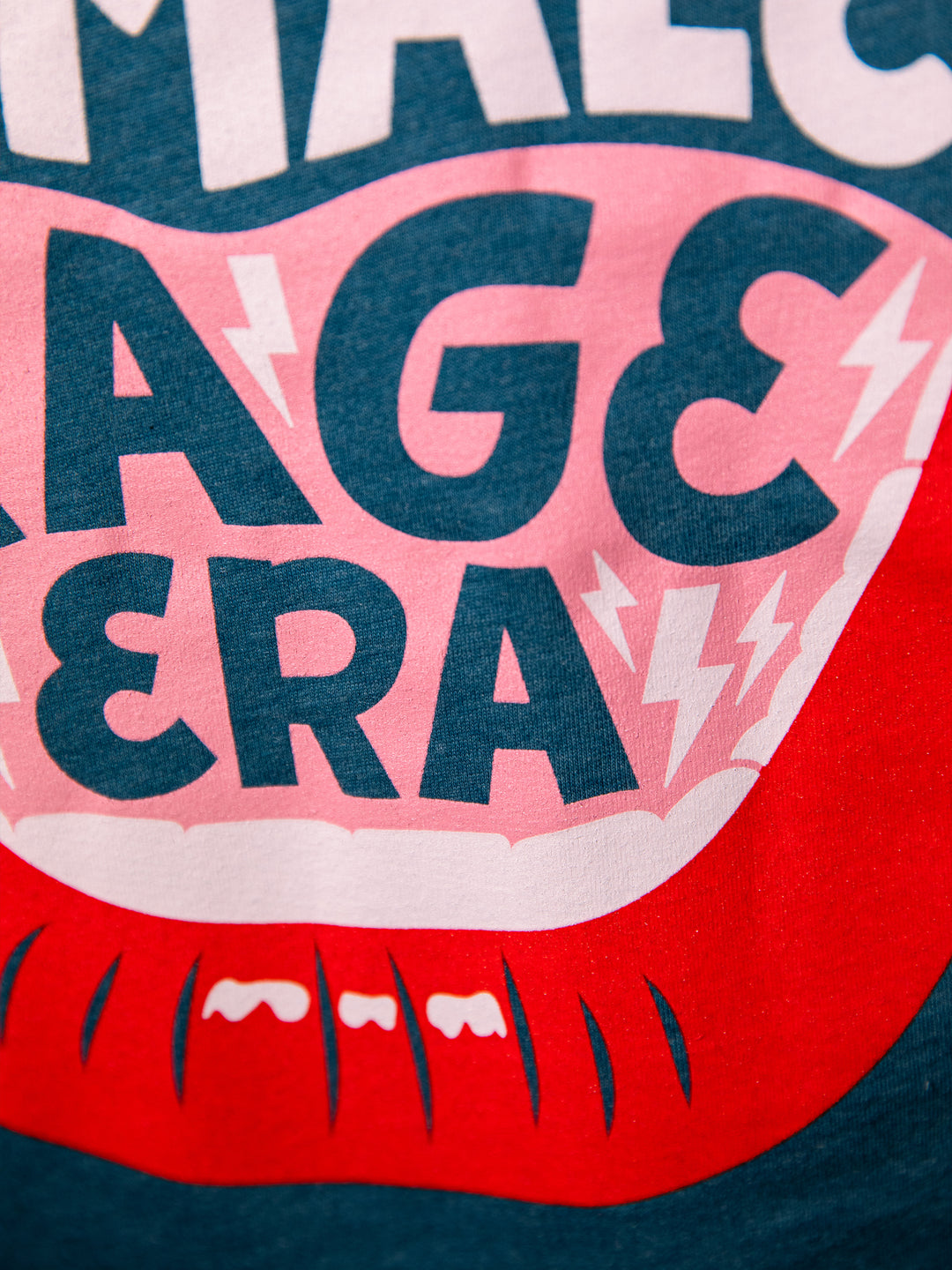 close up view of screen-printed graphic  with lips, open mouth red lips illustration and saying, "In my female rage era." on teal crew neck unisex t-shirt
