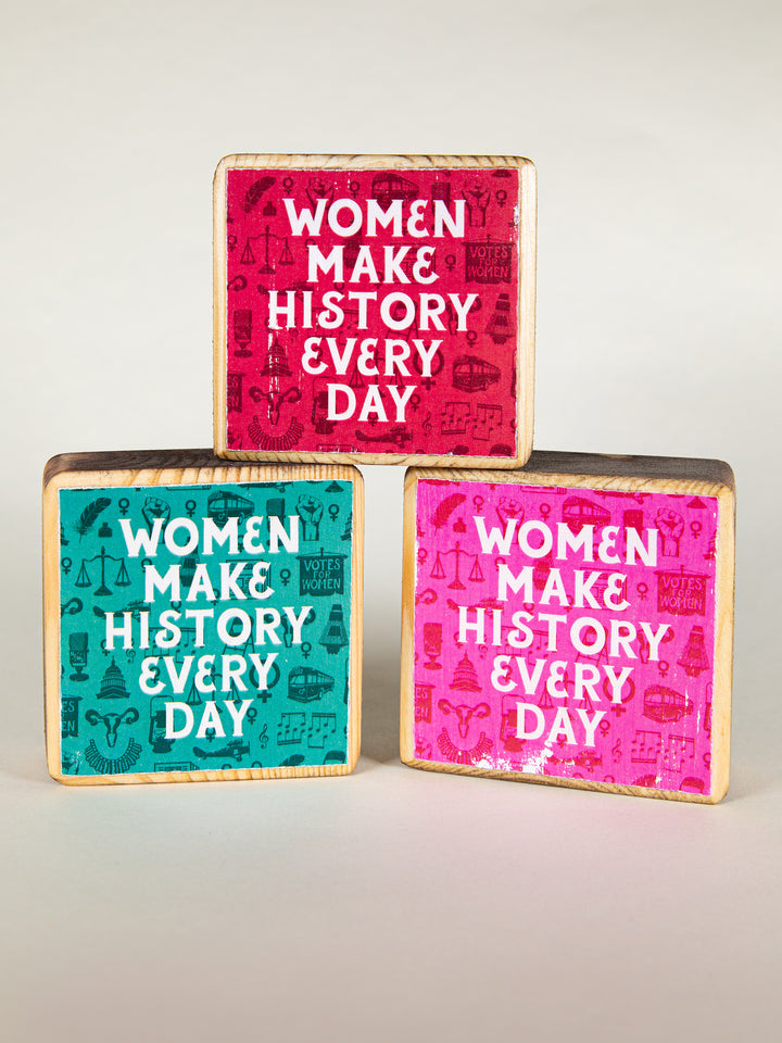 Red green and pink wood block stacked on each other on a cream background