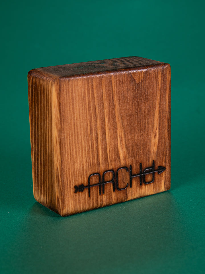 Back view of a stained bood block with an ARCHd logo branded on the bottom on a green background