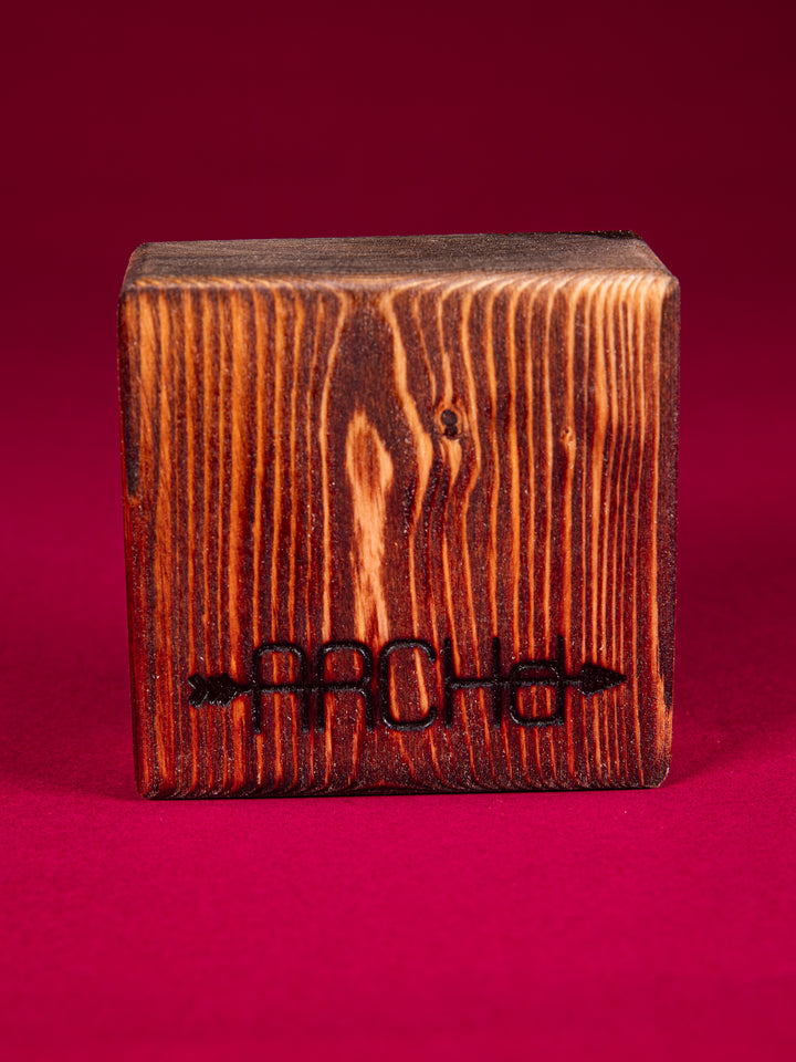 Back view of a stained bood block with an ARCHd logo branded on the bottom on a dark pink background