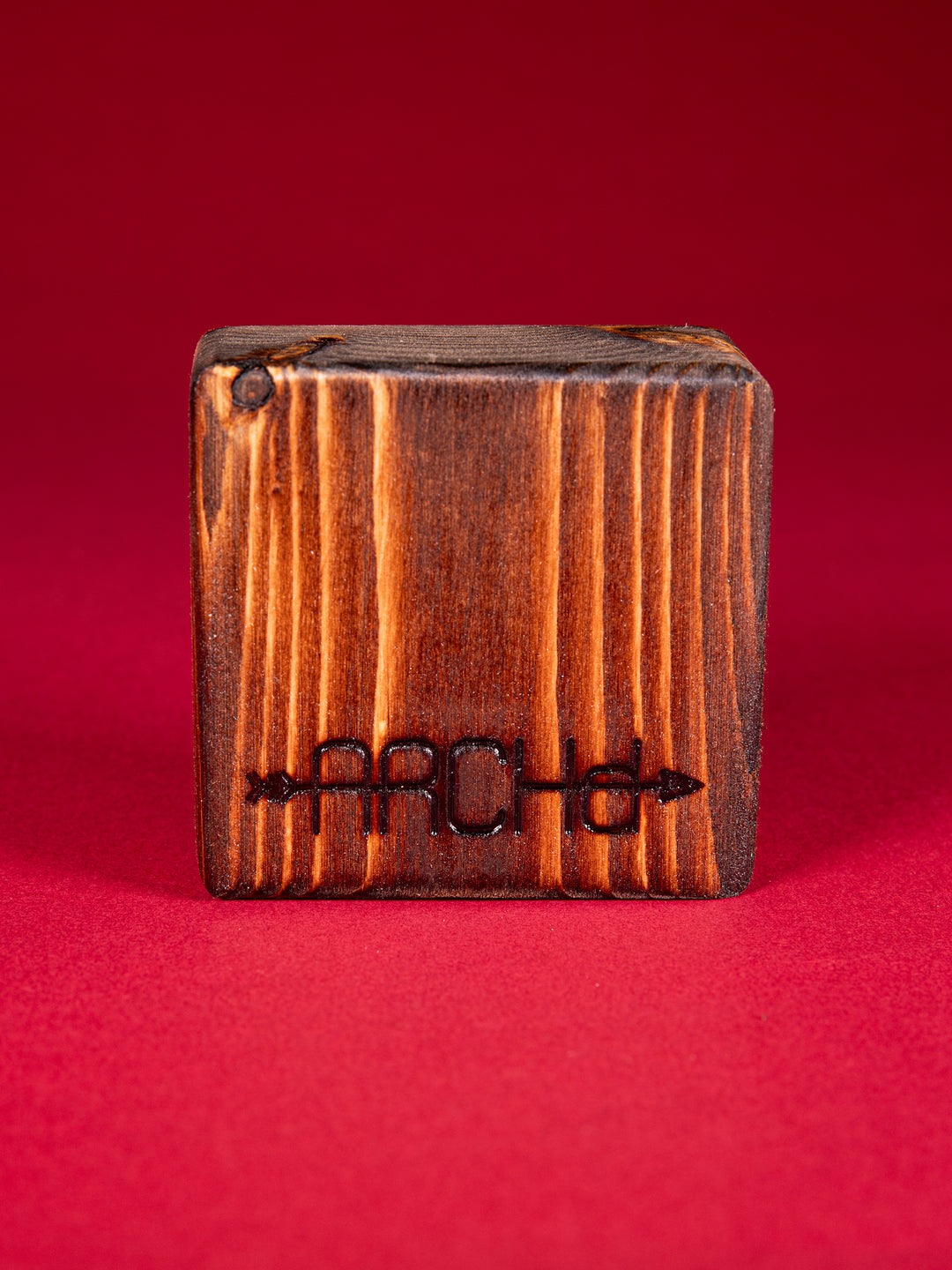 Back view of a stained bood block with an ARCHd logo branded on the bottom on a red background