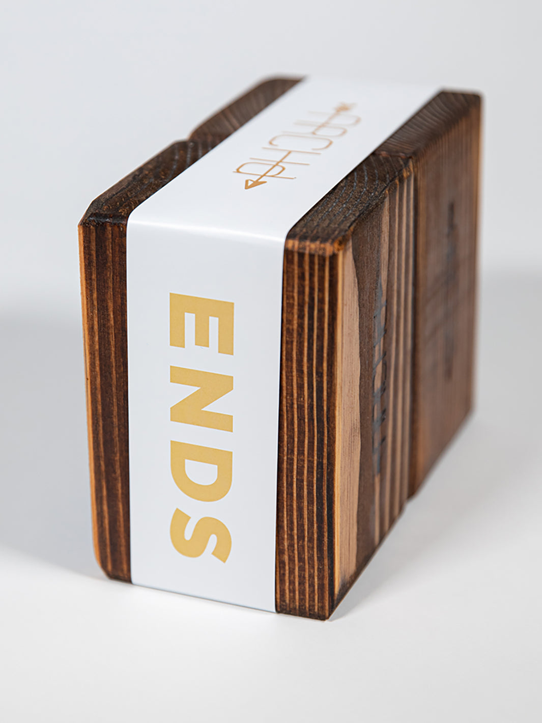 Back view of ARCHd handmade wood bookend set packaged with white paper branded sleeve on white background