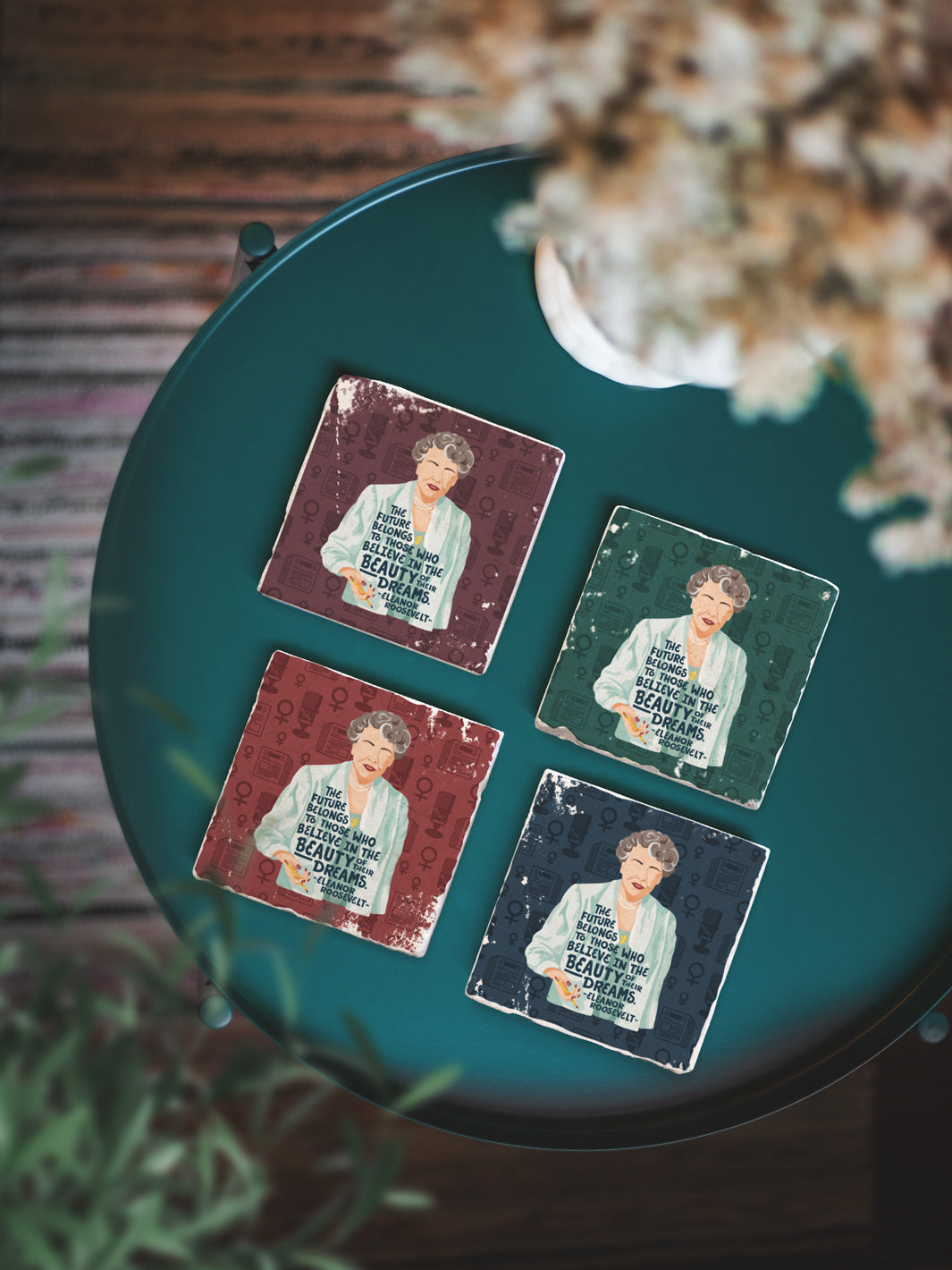 Illustration of Eleanor Roosevelt with her quote, "The future belongs to those who believe in the beauty of their dreams." marble coaster set of 4 on a teal table with plants. Eleanor Roosevelt art