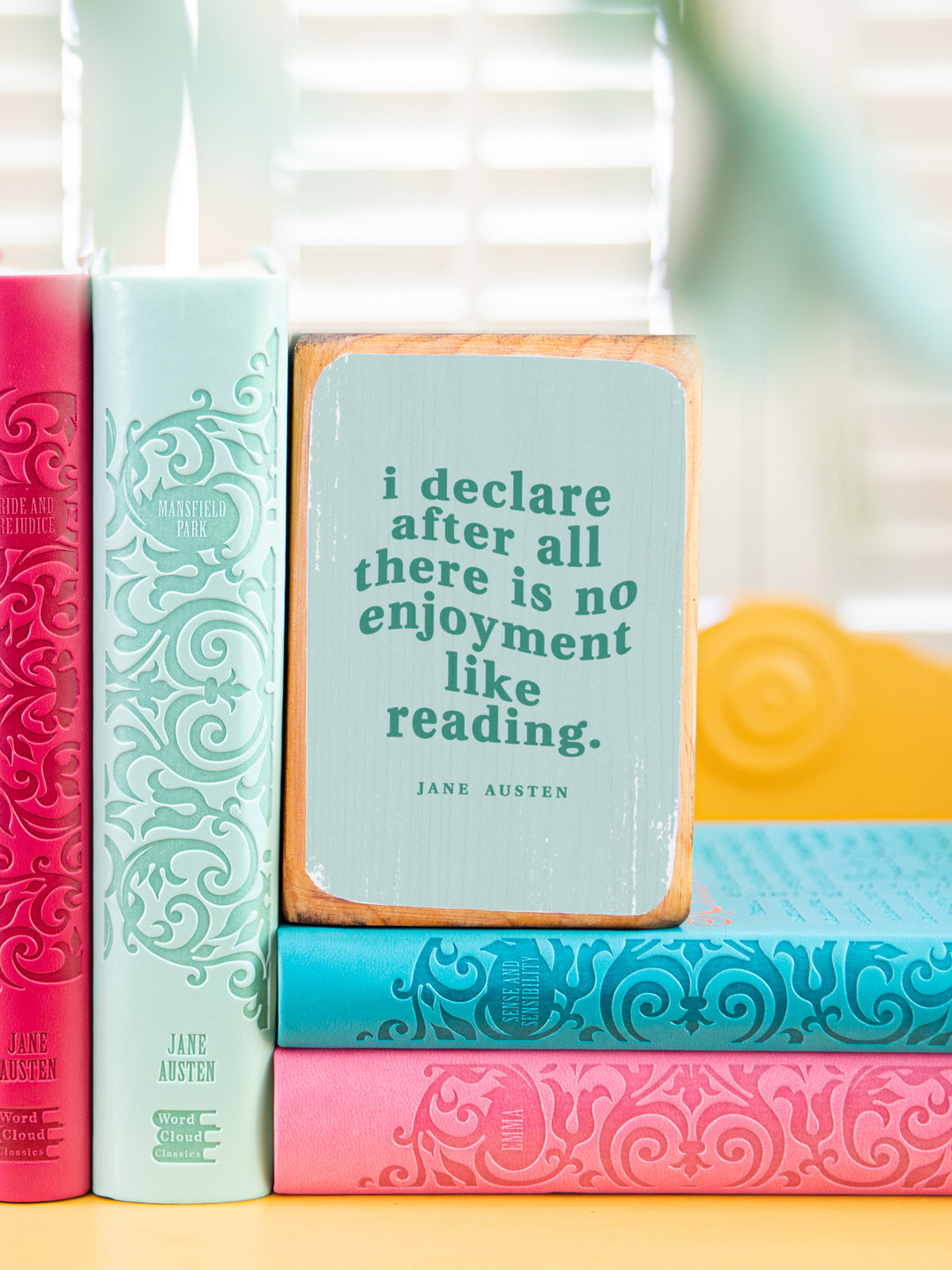 close up of Jane Austen quote bookend on a gold side table holding up two books and sitting on two books, quote reads I declare after all there is no enjoyment like reading. Jane Austen gifts