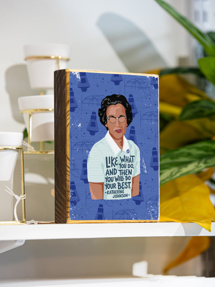 Lifestyle photo of katherine johnson wood art. Sitting on a table top next to plants. Katherine Johnson art