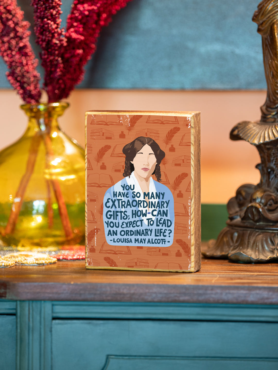 Louisa May Alcott 5x7 wood art on teal buffet with yellow vase and lamp behind. Louisa May Alcott gifts