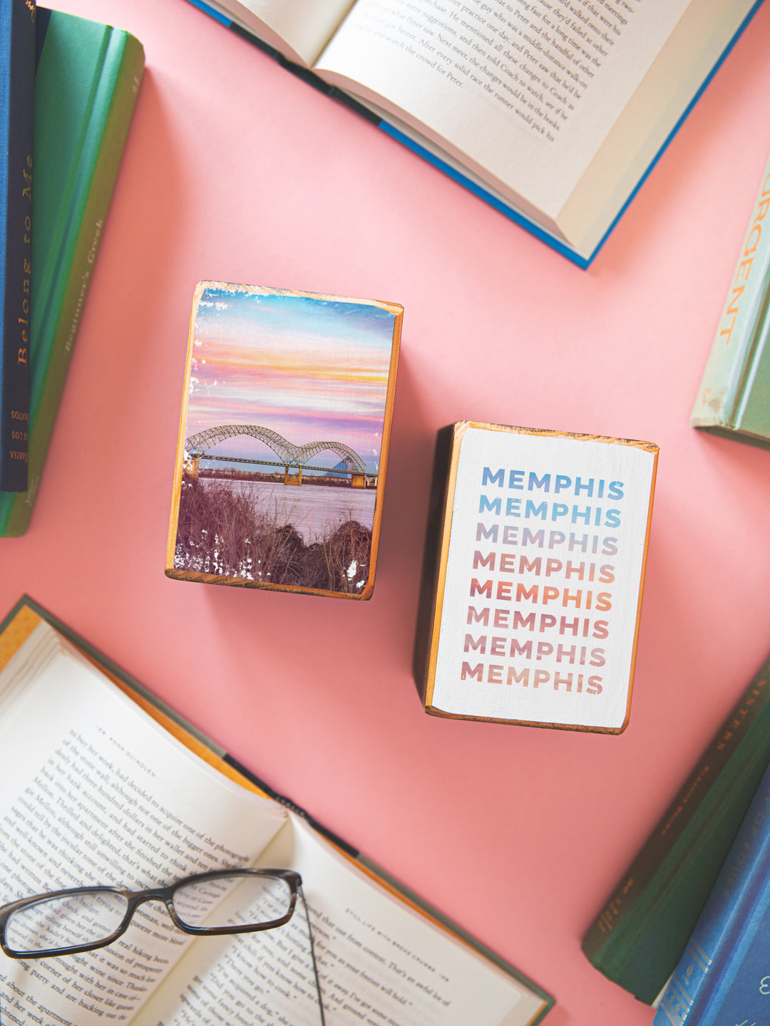 memphis bridge bookends on coral backgrounnd with books scattered around