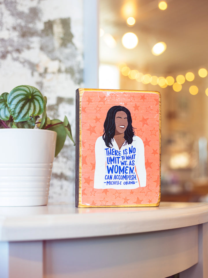 Feminist wood wall art decor of Michelle Obama illustration with quote, "There is not limit to what we, as women, can accomplish." on orange background with star illustrations. Michelle Obama merchandise
