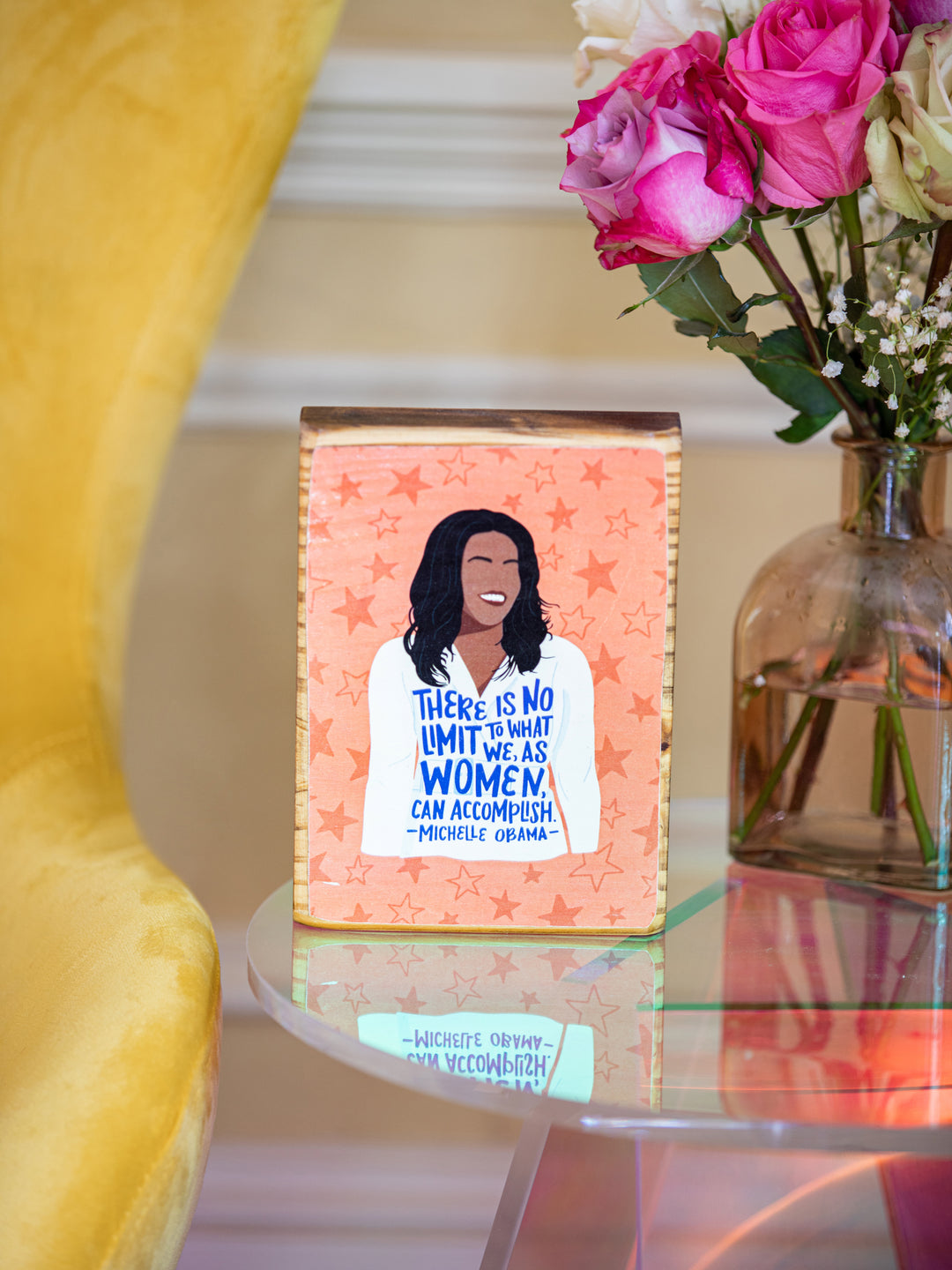Feminist living room decor of Michelle Obama illustration with quote, "There is not limit to what we, as women, can accomplish." on orange background with star illustrations. Michelle Obama merchandise
