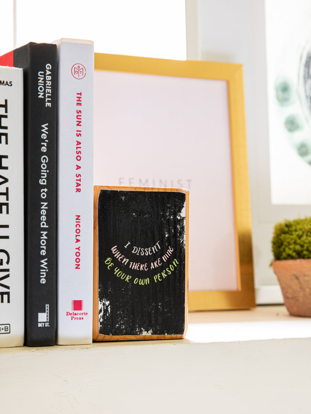 Close up right side of wood bookend set with Ruth Bader Ginsburg sayings, "I dissent," "When there are nine," and "Be your own person," on black background. Ruth Bader Ginsburg art