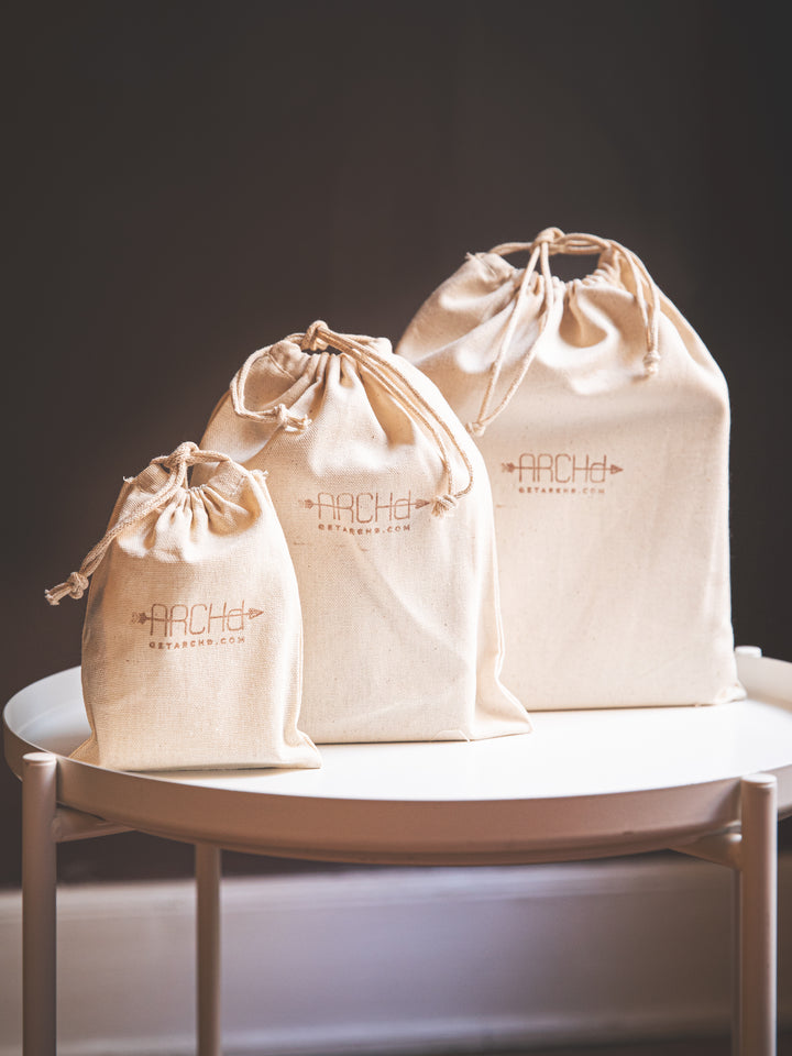 white muslin bags with archd logo stamped across the front